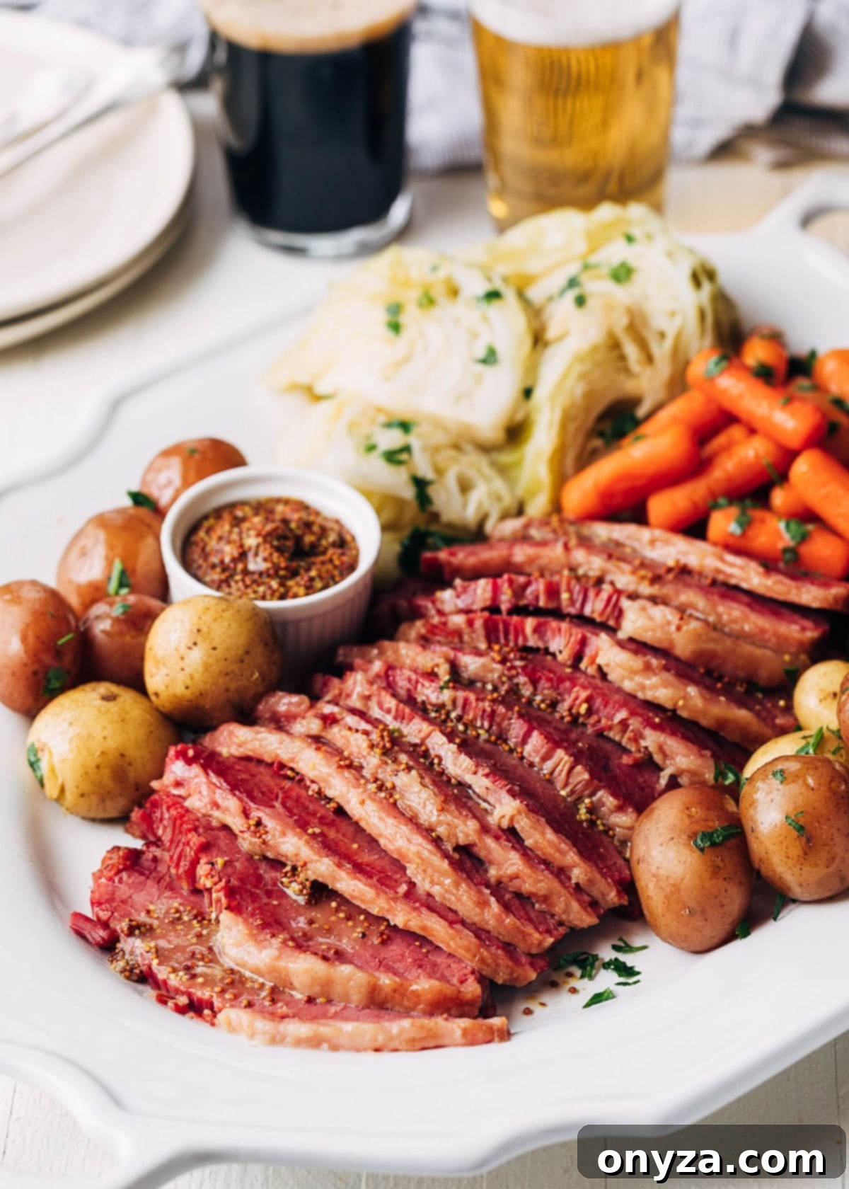 slices of instant pot corned beeef on a white platter with baby potatoes, carrots, and cabbage wedges