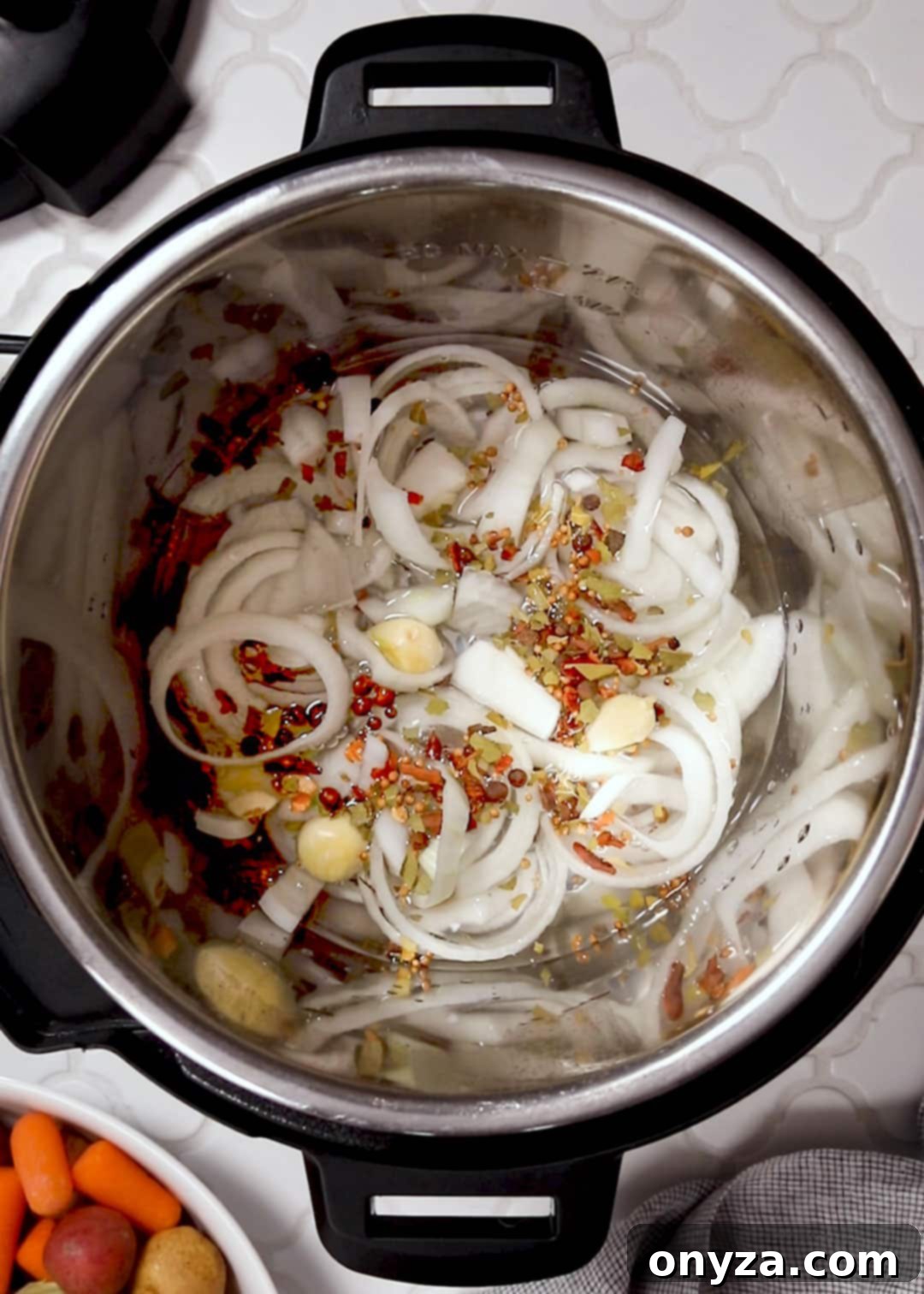 sliced onions, whole garlic cloves, and pickling spice in the bottom of an Instant Pot.