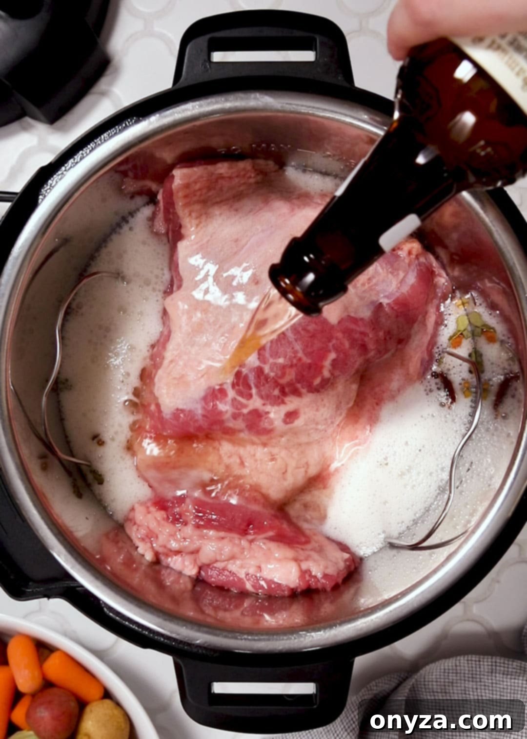 beer being poured from a bottle over a raw corned beef brisket in an Instant Pot