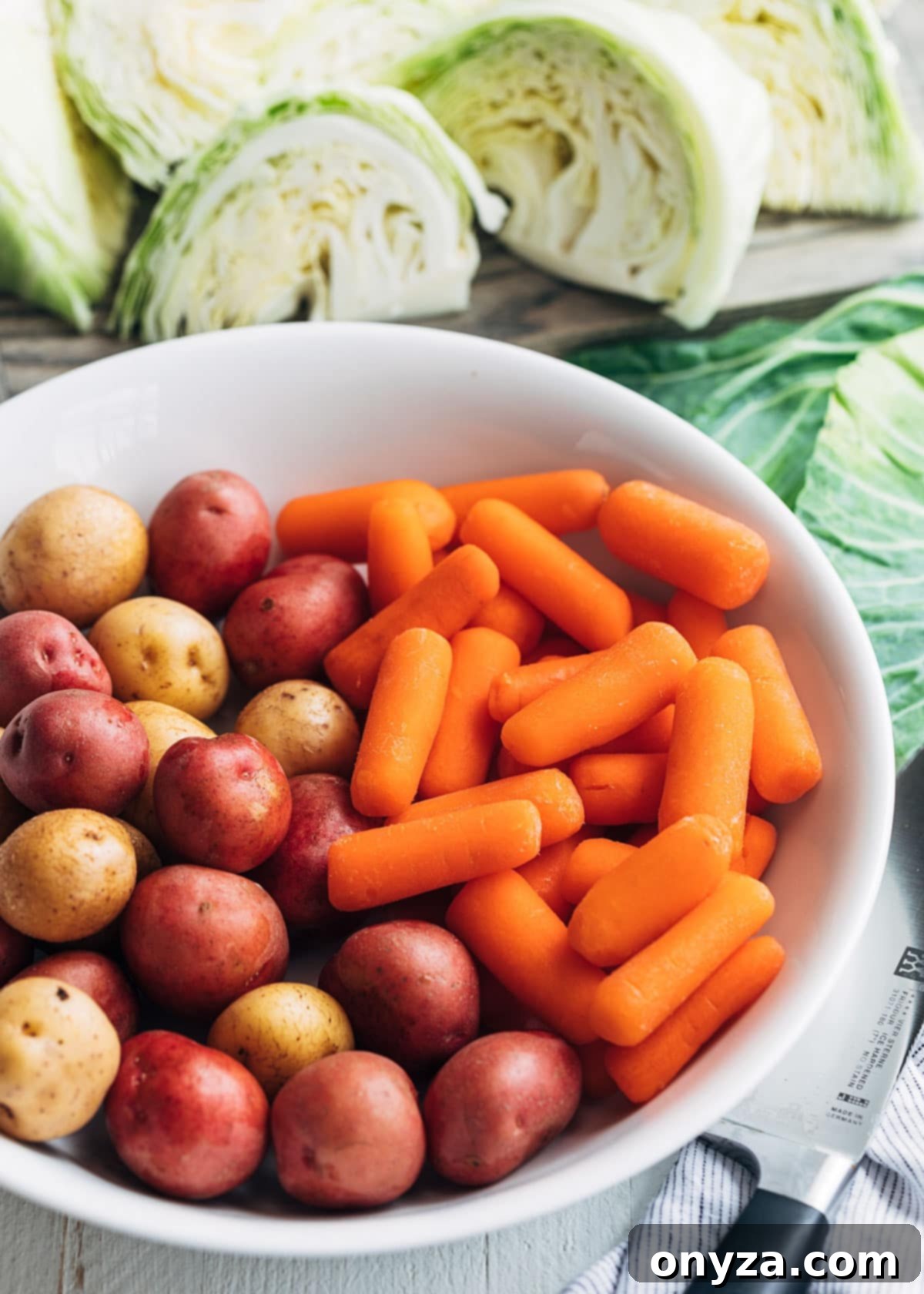 small potatoes and baby carrots in a white bowl surrounded by green cabbage wedges
