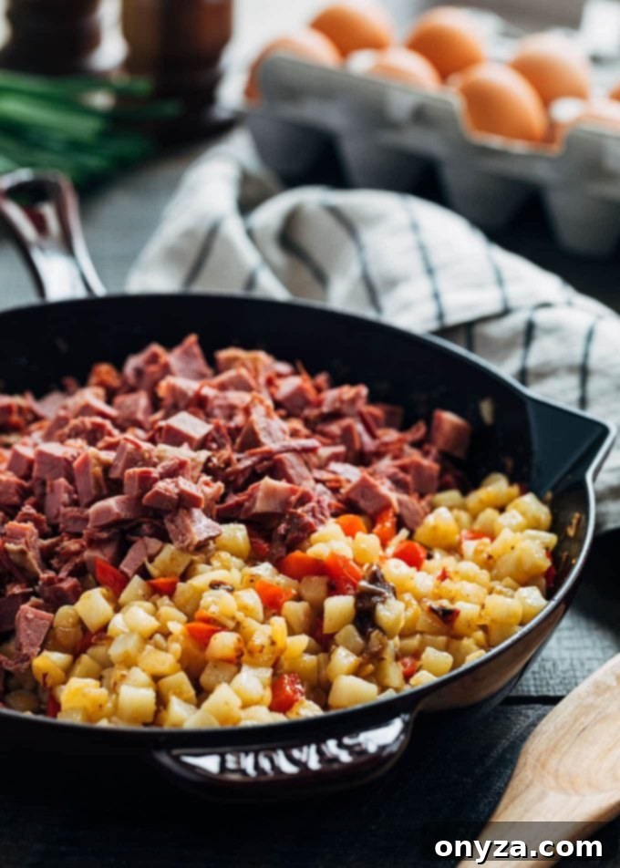 Hearty Corned Beef Hash and Eggs 3 Close-up of diced potatoes and tender corned beef sizzling in a cast iron skillet, key ingredients for homemade hash