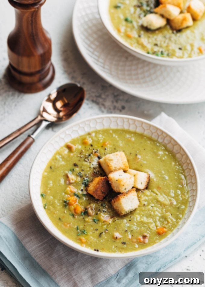 Three bowls of the best split pea soup recipe, each garnished with fresh herbs and served on a rustic wooden surface.