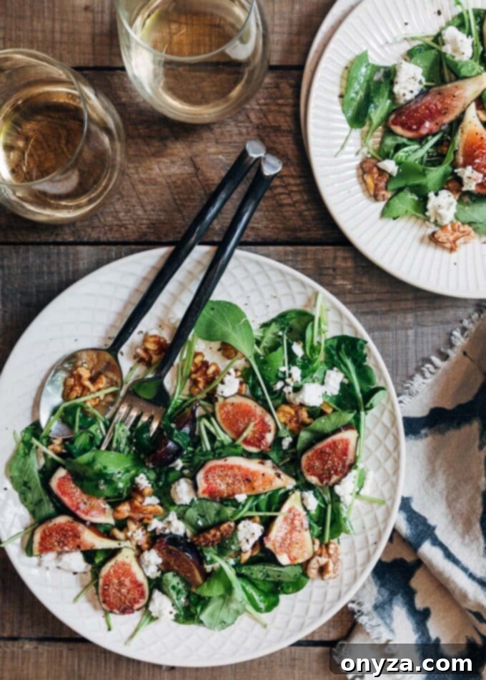 fig salad with baby arugula on ivory plates with glasses of white wine