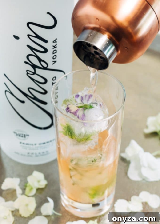 Pouring Chopin Spring Equinox vodka cocktail into a glass with flower ice cubes