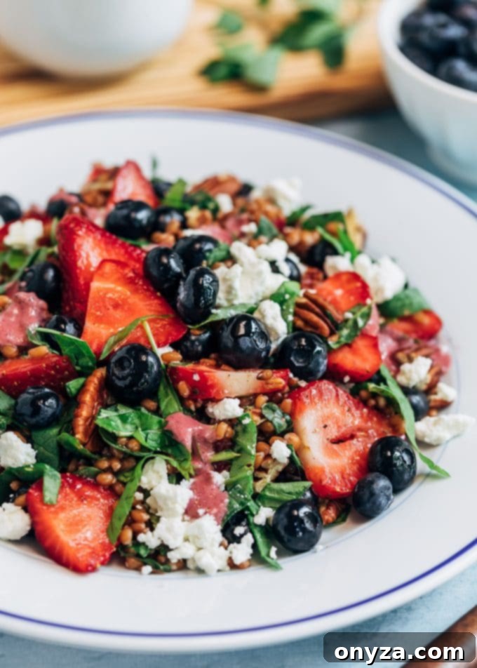 Prepared Wheat Berry Salad with Mixed Berry Vinaigrette, garnished with fresh berries and goat cheese
