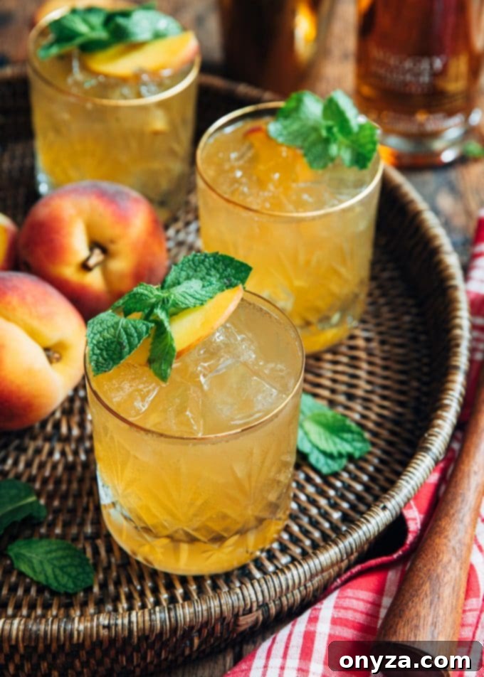 Two Bourbon Peach Smash cocktails, garnished with mint and peach slices, served on a wicker tray for a refreshing summer drink.
