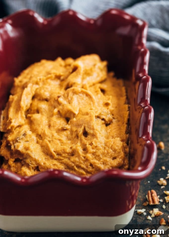 Smooth, spiced pumpkin bread batter in a classic Emile Henry loaf pan, ready for the oven and crumb topping.