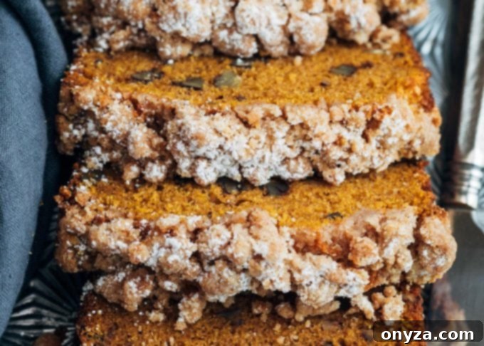 Closeup of slices of moist pumpkin crumb bread, revealing the tender interior and golden, buttery streusel topping.