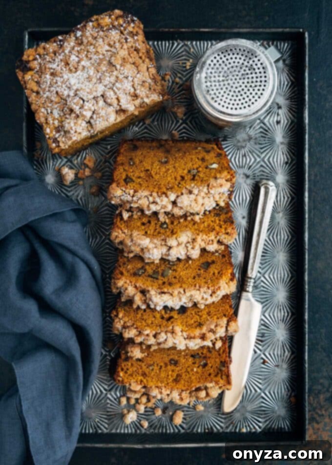 Warm slices of streusel-topped pumpkin bread arranged on a baking sheet, showcasing the crispy topping and soft interior.