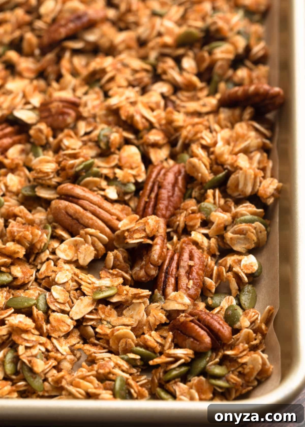 Unbaked Pumpkin Granola spread evenly on a parchment-lined baking sheet, ready to be transformed into a golden, fragrant treat.