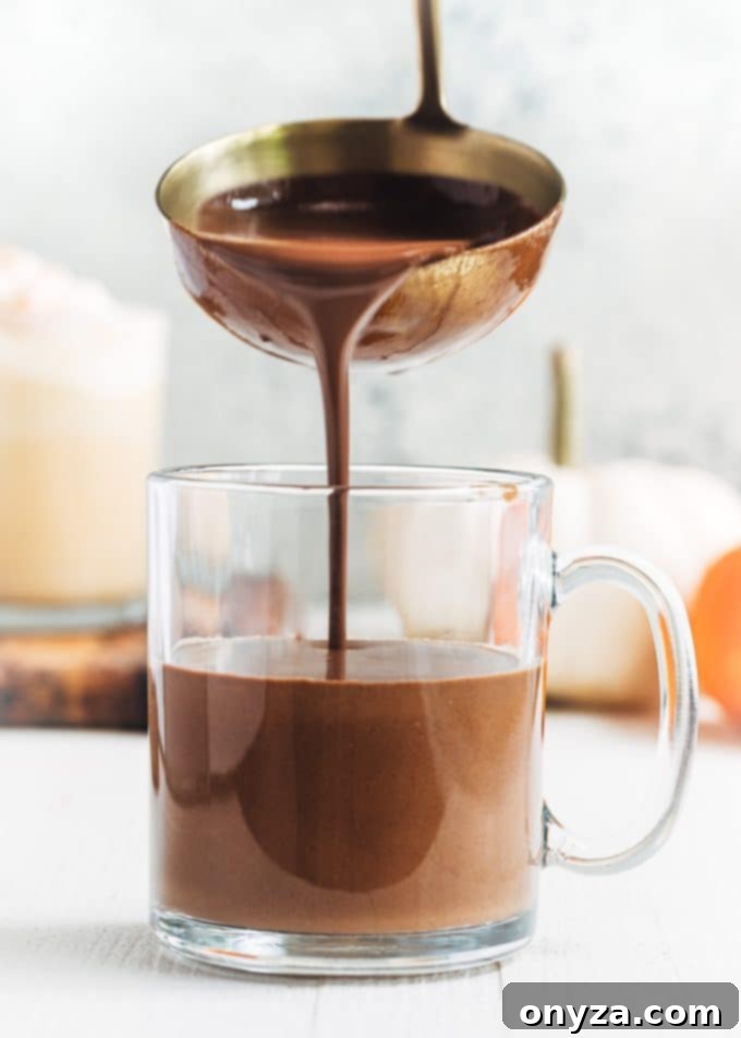 pouring dark chocolate pumpkin spice hot chocolate with a ladle