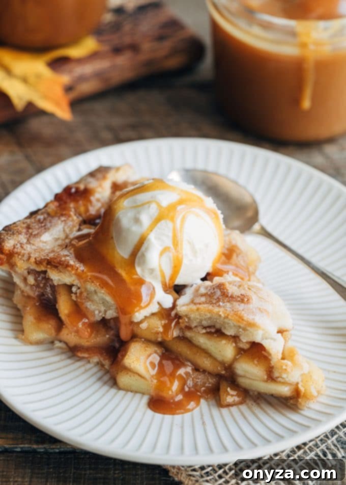 Warm apple cider caramel generously drizzled over a scoop of vanilla ice cream atop a slice of apple pie.