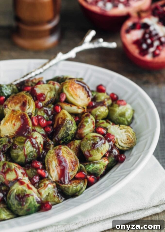 Roasted Brussels sprouts with vibrant pomegranate arils in a white serving dish, ready to be enjoyed as a festive side.