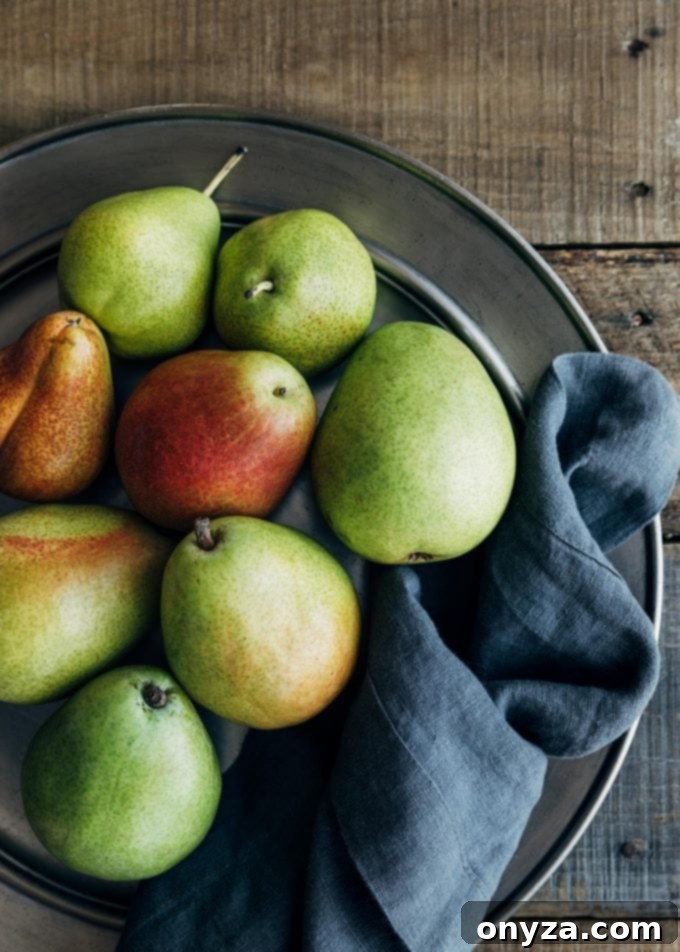 Two varieties of fresh d'Anjou and Forelle pears displayed artfully on a pewter plate, ready for slicing