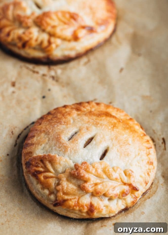 Beautifully baked caramel apple hand pies arranged on a parchment-lined baking sheet, golden and inviting for serving
