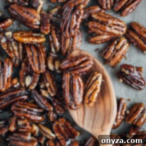 Stovetop Caramel Crunch Pecans 4 Caramelized pecans on a baking sheet with a wooden spoon