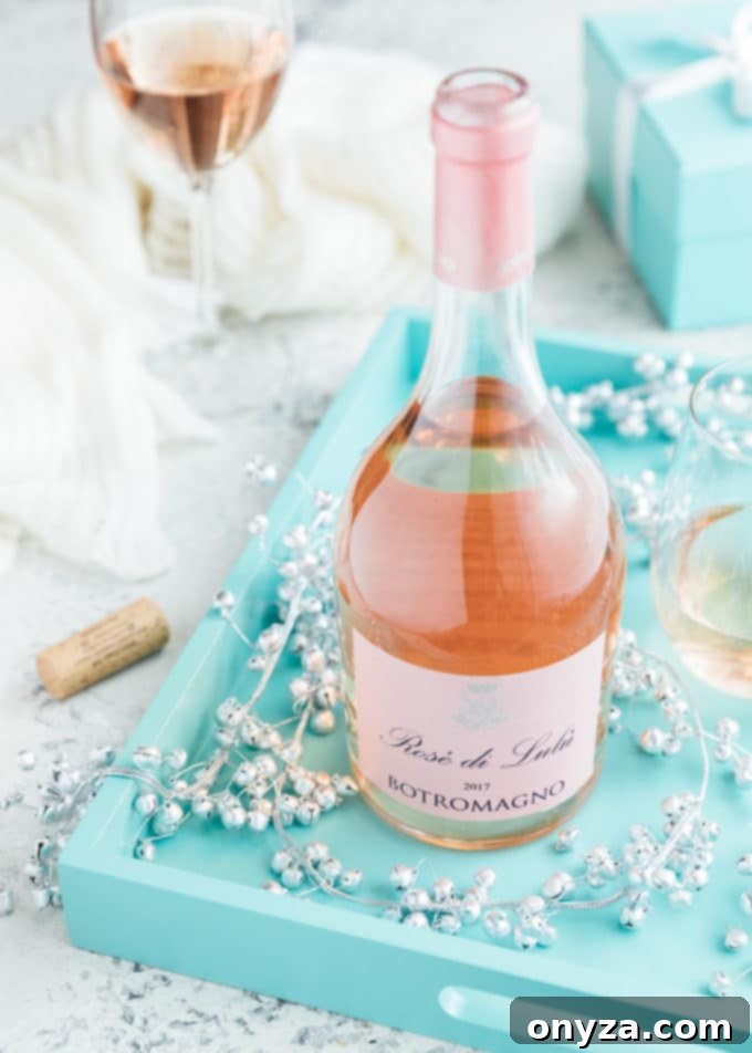 Bottle of Botromagno ‘Rose di Lulu’ wine on a blue serving tray with silver bells, evoking a festive and elegant holiday ambiance