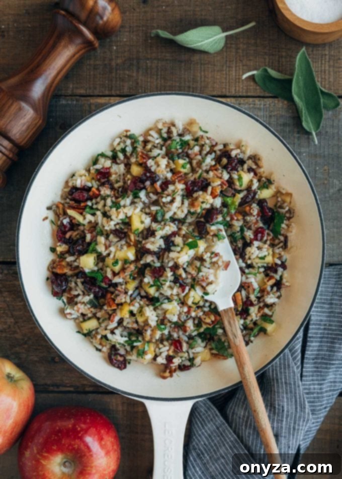 A close-up view of wild rice, cranberry, and apple stuffing in a white pan, ready to be used for Cornish hens.