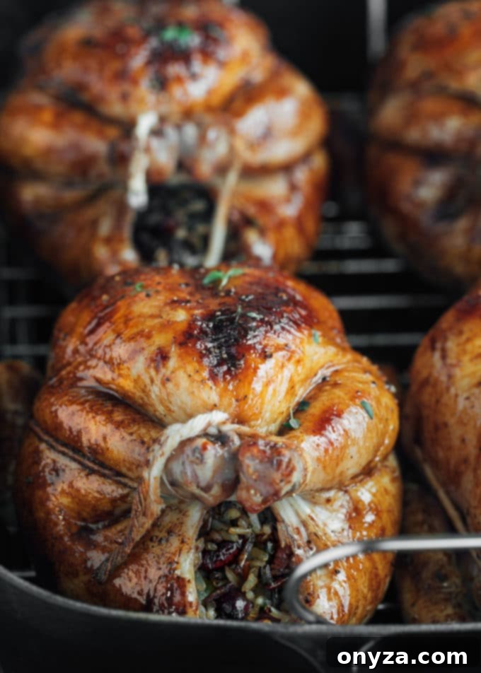 A perfectly roasted and glazed Cornish hen, golden brown and glistening, served in a cast iron roasting pan.