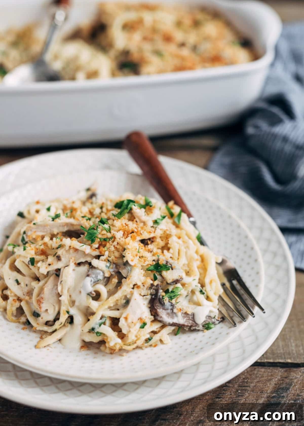 Creamy Turkey Tetrazzini 2 turkey tetrazzini on an ivory plate with a wood-handled fork