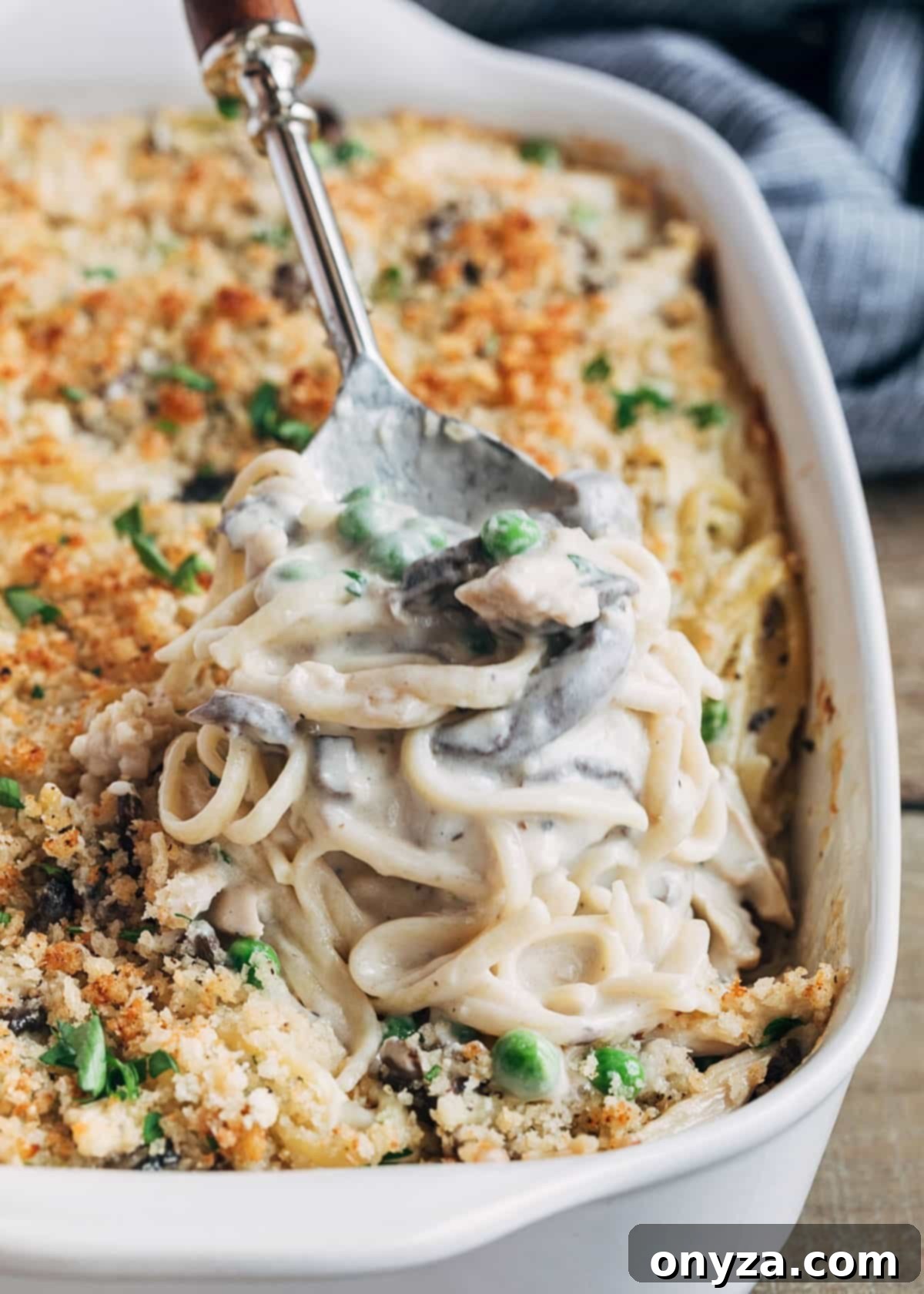 Creamy Turkey Tetrazzini 6 baked turkey tetrazzini being scooped from a white baking dish