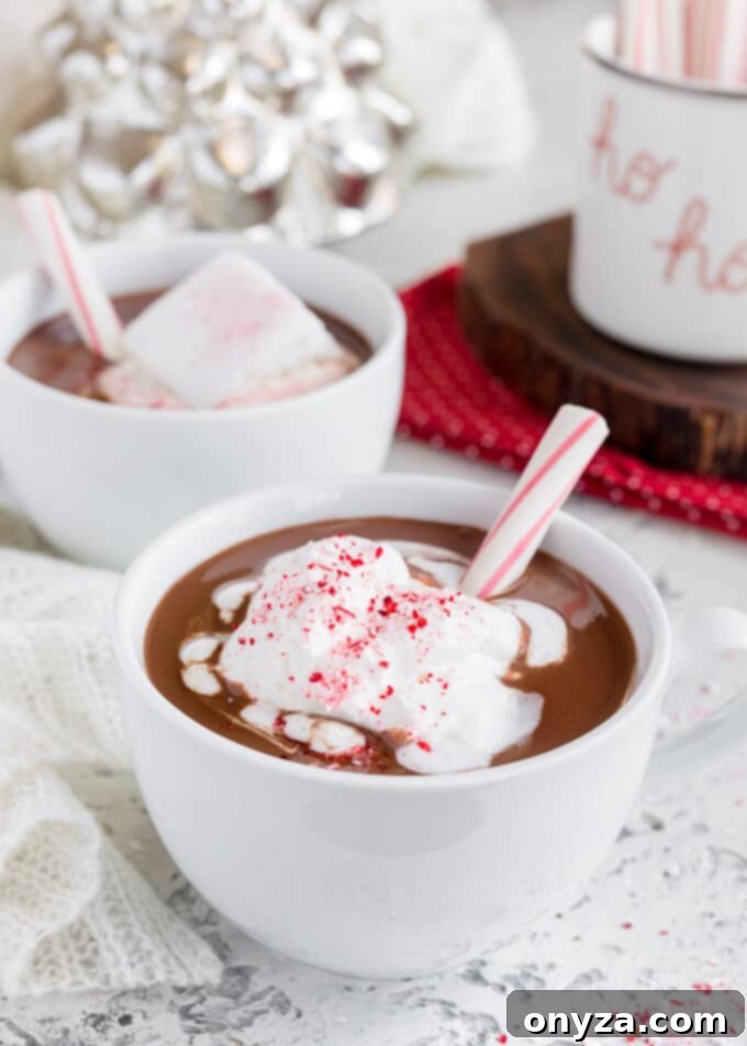 mugs of peppermint hot chocolate with whipped cream and candy cane sticks