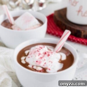 mugs of peppermint hot chocolate with whipped cream and candy cane sticks