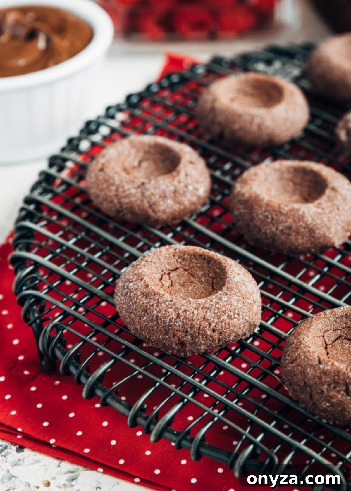 unfilled baked chocolate thumbprints on a black wire cooling rack 