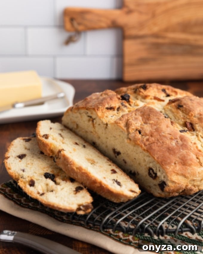 Classic Irish-American Soda Bread 2 sliced loaf of American-style Irish Soda bread with raisins on a wire cooling rack, with a block of Irish butter in the background