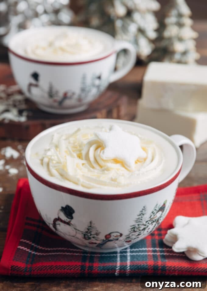 white hot chocolate in large mugs with whipped cream and snowflake shaped marshmallows