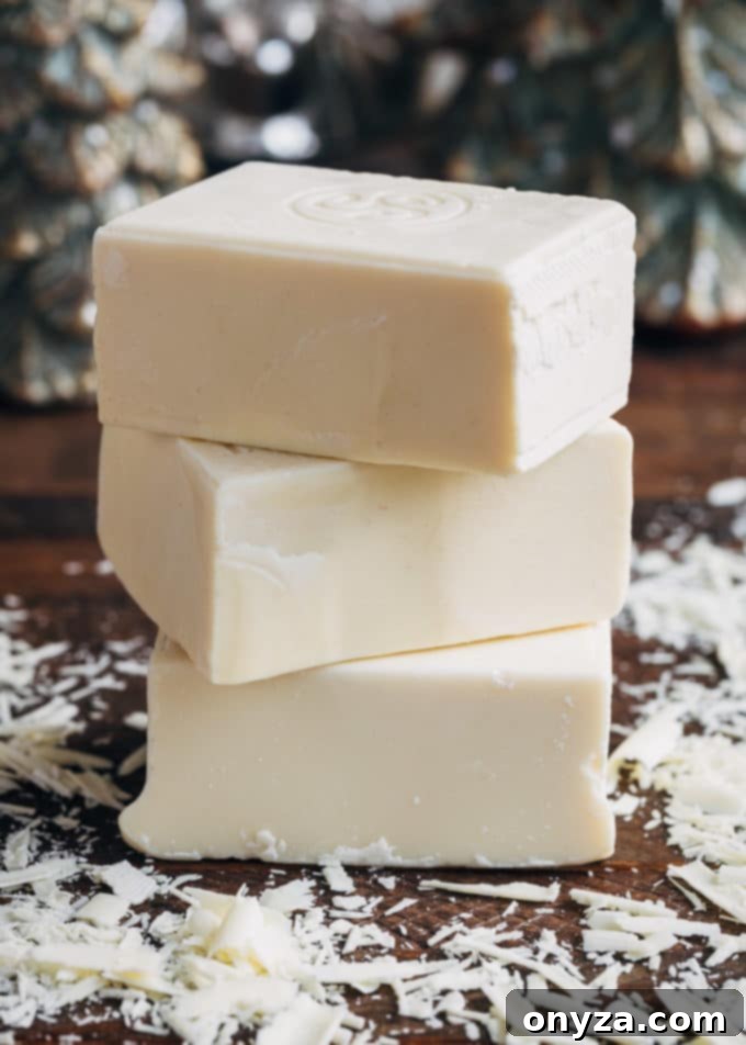 3 blocks of white hot chocolate on a wood board with white chocolate shavings