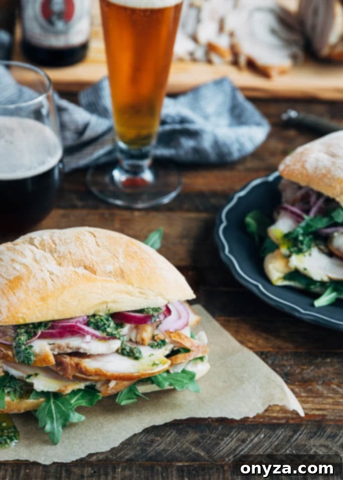 Two enticing Porchetta Sandwiches, featuring layers of succulent pork, vibrant salsa verde, and pickled onions on ciabatta, artfully presented with glasses of cold beer, ready for enjoyment.