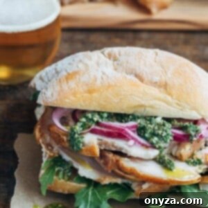 Porchetta sandwich with salsa verde and pickled onions on a ciabatta roll