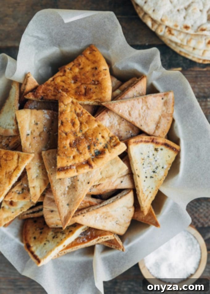 overhead shot of a ceramic bowl filled with golden baked pita chips, ready for serving