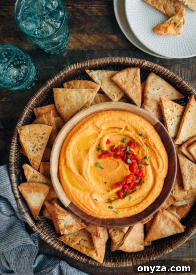 round serving platter of roasted red pepper hummus with pita chips