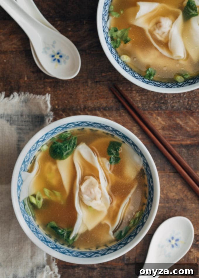 bowl of homemade wonton soup with baby spinach and sliced scallions