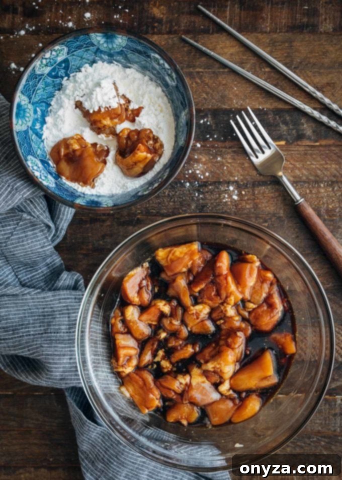 Cubed chicken thighs marinating in a mixture of soy sauce and egg, preparing for the first stage of the General Tso's Chicken recipe