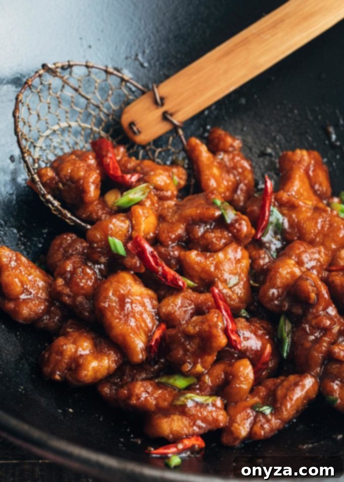 General Tso's chicken, featuring succulent pieces of fried chicken coated in a glossy, rich sauce with dried red chilies, cooking in a wok