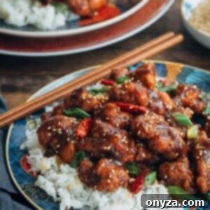 General Tso's Chicken over jasmine rice on a plate with chopsticks