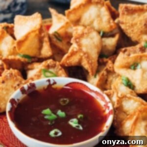 deep fried crab rangoon puffs on a plate with sweet and sour dipping sauce