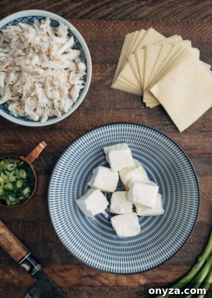 ingredients for crab rangoon in bowls on a wood board