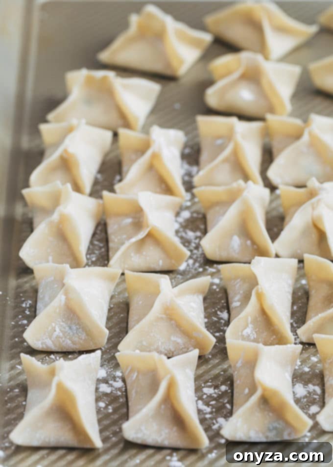 folded crab rangoon wontons on a baking sheet