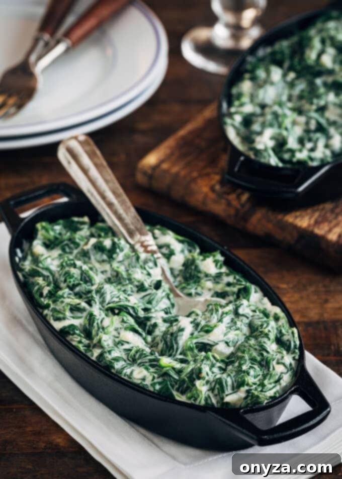 Rich and creamy homemade creamed spinach in a cast iron gratin with a serving spoon, ready to be enjoyed.