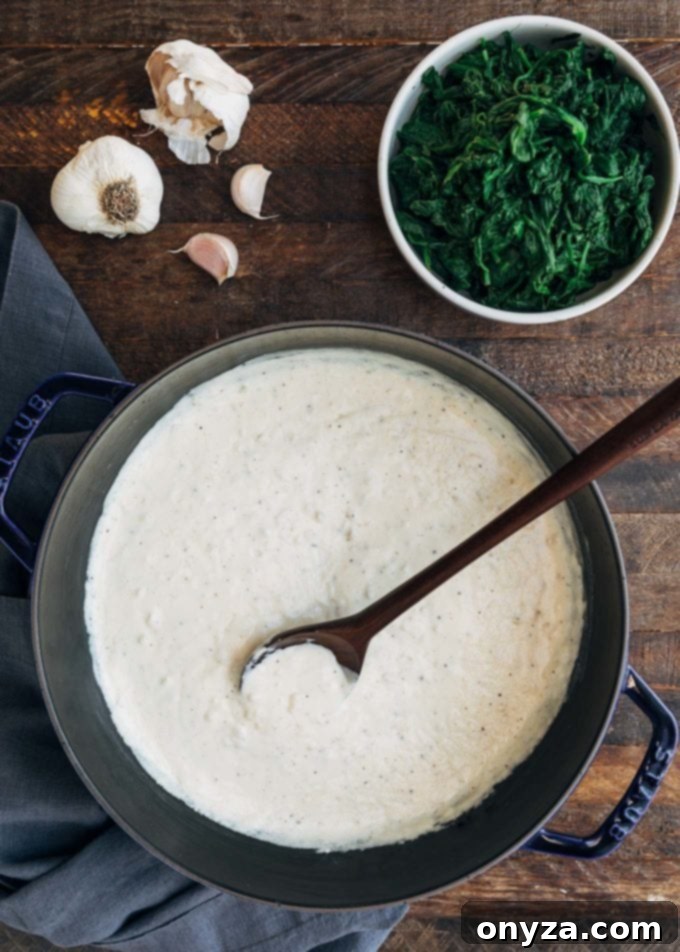 Creamy white sauce for creamed spinach being stirred in a saucepan.