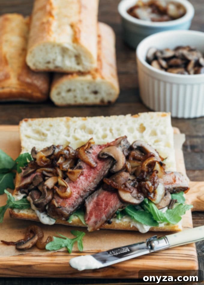 Unrivaled Steak Sandwich 4 Open-faced steak sandwich showing layers of pan-seared steak, sautéed mushrooms, and caramelized onions