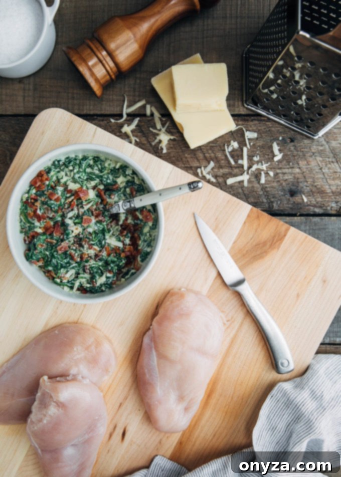 Close-up of raw chicken breasts on a cutting board next to a bowl of creamy spinach and cheese filling, ready for preparation.