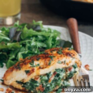 Spinach stuffed chicken breast, beautifully plated on an ivory dish with fresh salad greens on the side.