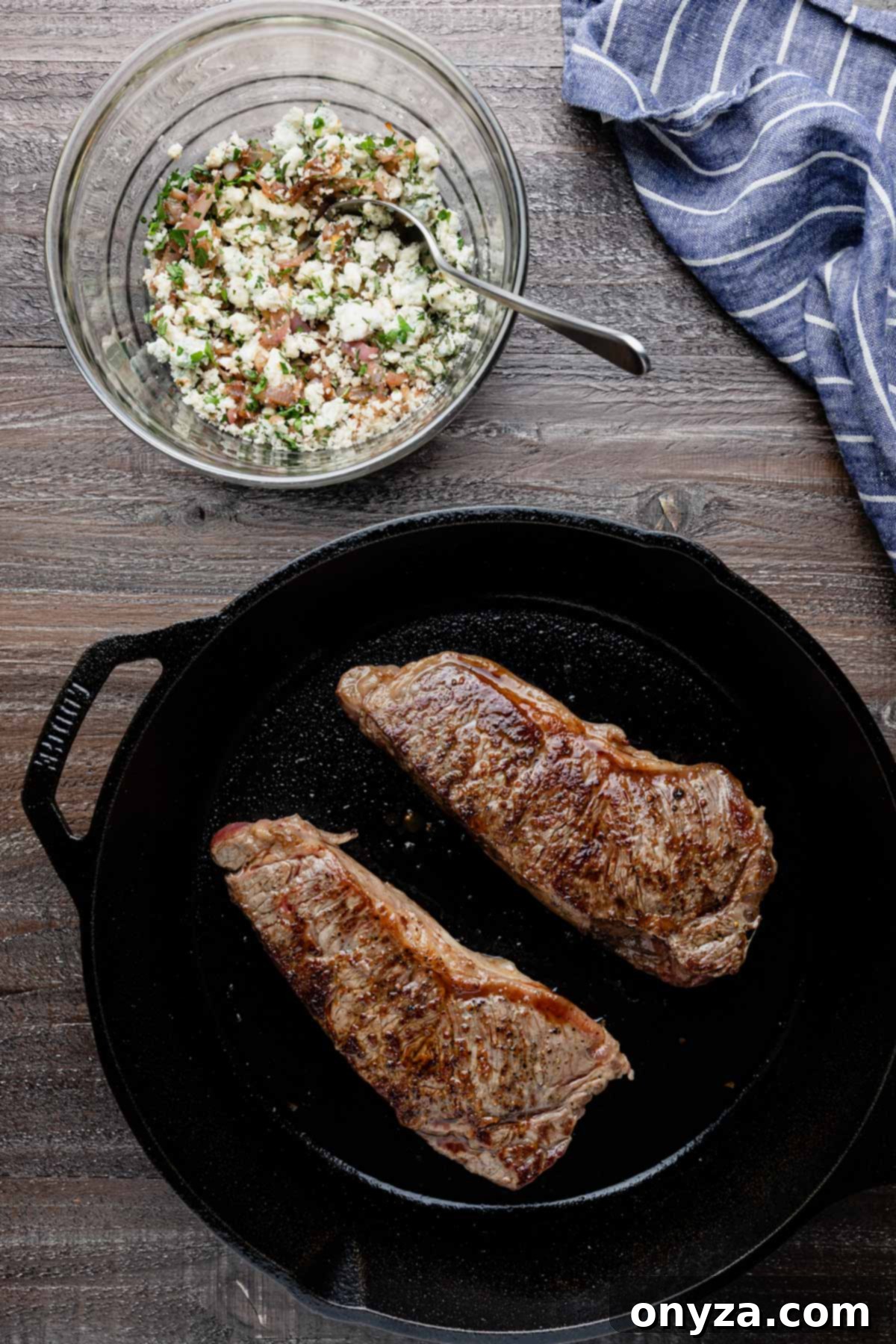 Balsamic Shallot Steak with Blue Cheese Crust 5 seared strip steaks in a cast iron pan next to a bowl of blue cheese crust mixture