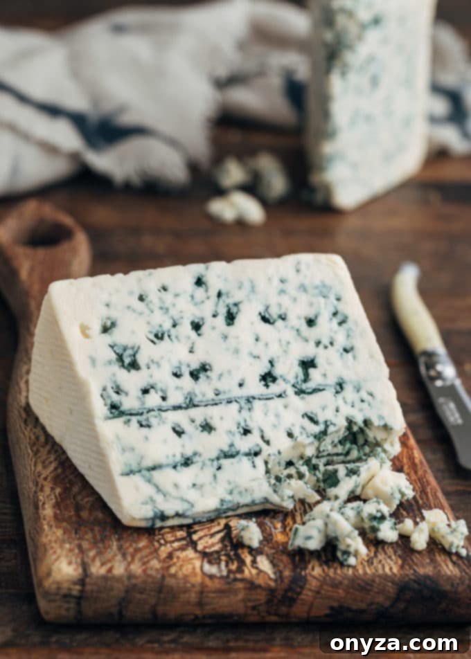 Creamy Buttermilk Blue Cheese Dressing 2 A beautiful wedge of Danish blue cheese rests on a rustic wooden board, ready to be crumbled for homemade dressing.