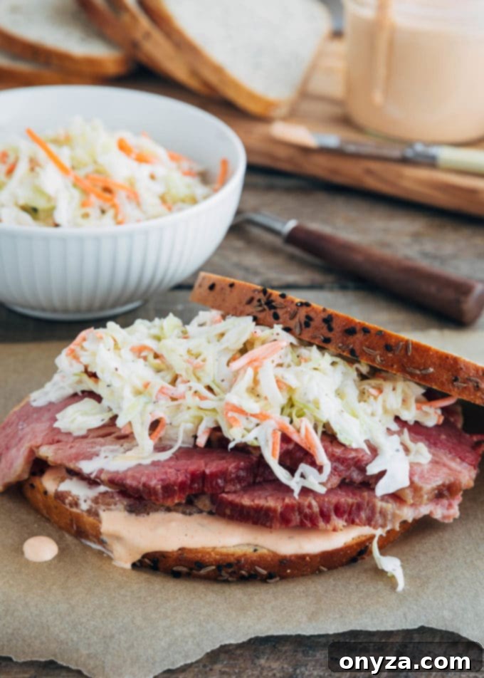 Step-by-step assembly of a corned beef sandwich, showing layers of rye bread, Russian dressing, corned beef, and coleslaw